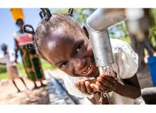 Une fillette au Zimbabwe boit de l'eau propre et salubre un puits réhabilité avec le soutien de l'ONU. Photo : Unicef, Karin Schermbrucker